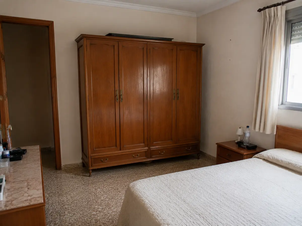 Dormitorio con armario antiguo de madera independiente antes de su sustitución por un armario a medida.