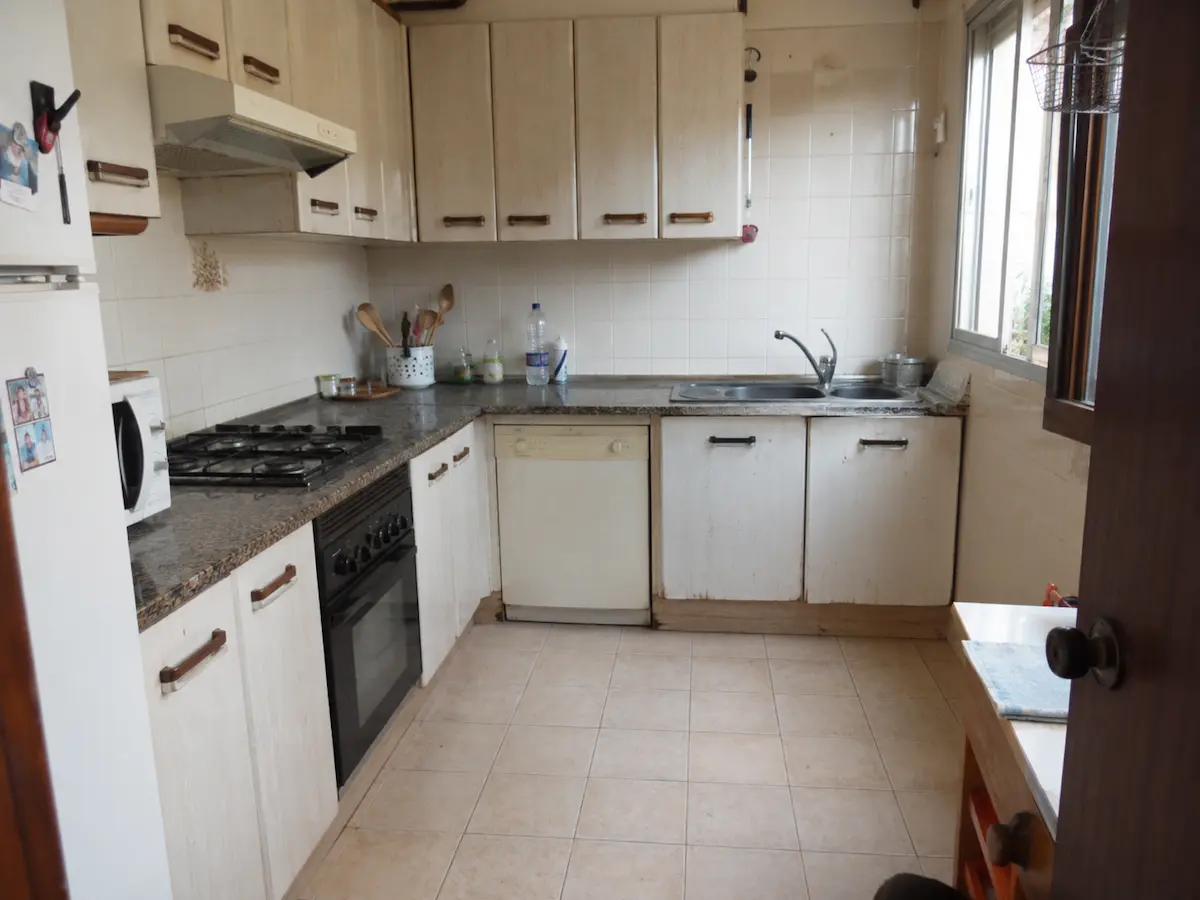 Cocina antigua con muebles de madera desgastados antes de renovar la carpintería.