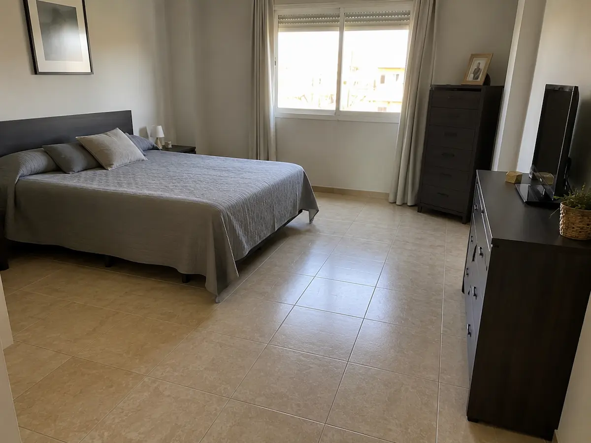 Dormitorio con suelo cerámico antiguo de color beige antes de renovar el pavimento de la vivienda.